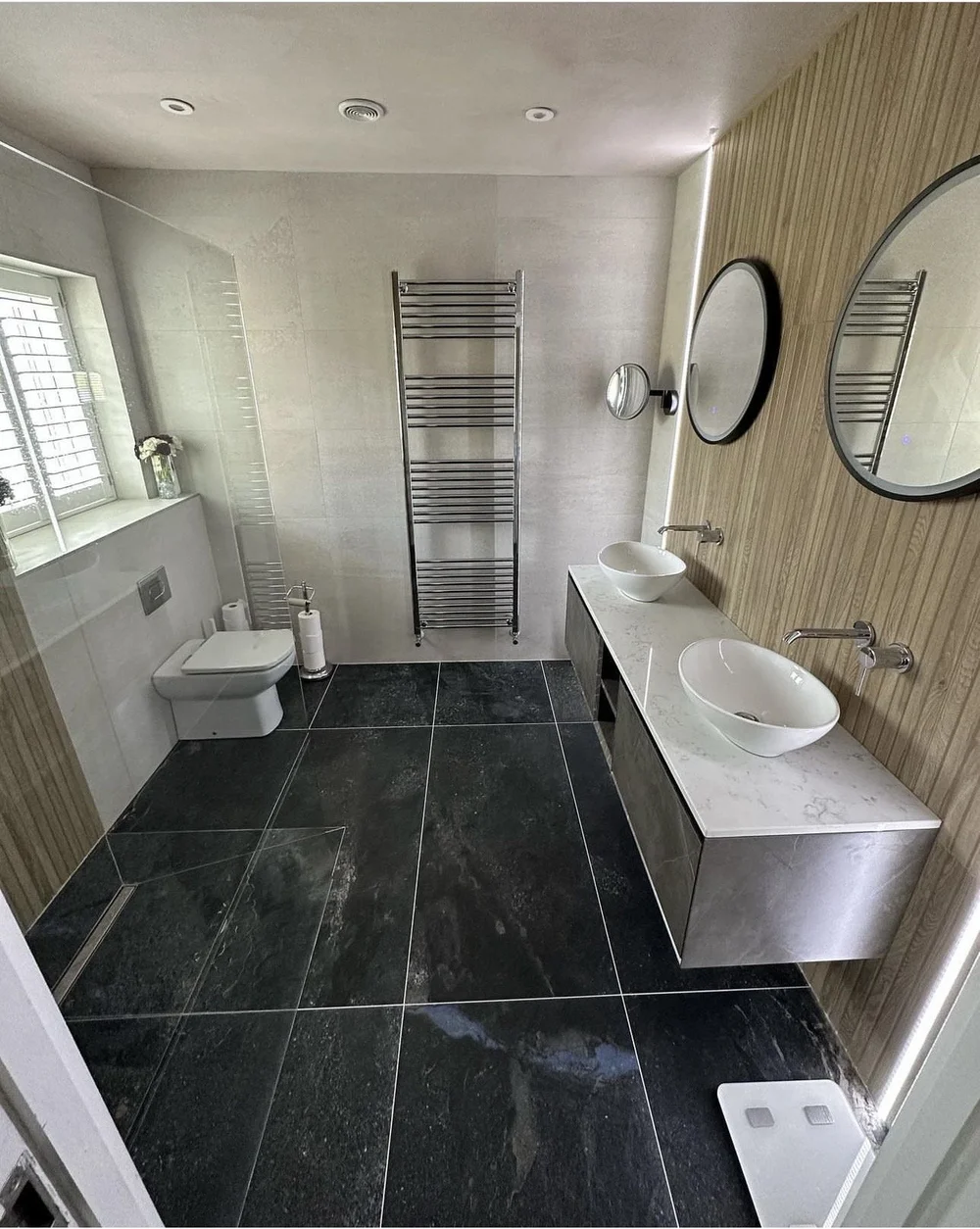 Slate-floored master bathroom with oak fluted feature wall, twin vessel basins and quartz vanity — bathroom design