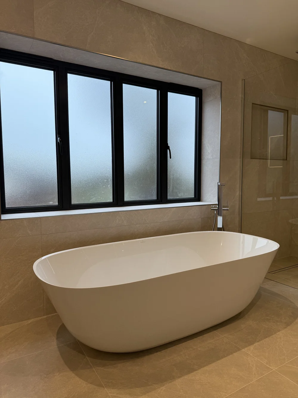 Freestanding bath under crittall window in stone-tiled master bathroom — Sunningdale, Berkshire