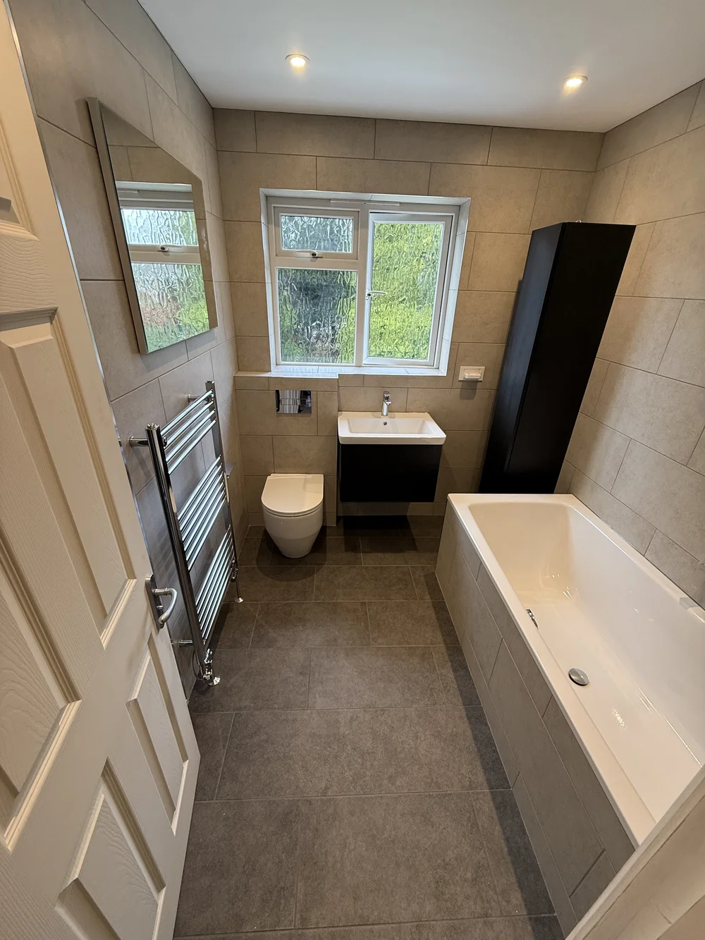 Compact family bathroom with black vanity, wall-hung WC and built-in bath — bathroom installation in Sunningdale