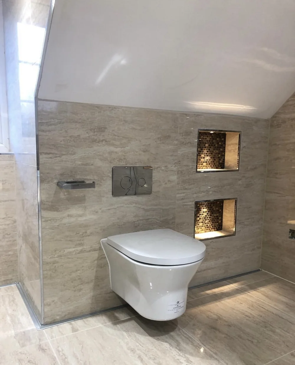 Travertine wet room with wall-hung WC and illuminated mosaic niches — bathroom renovation in Sunningdale