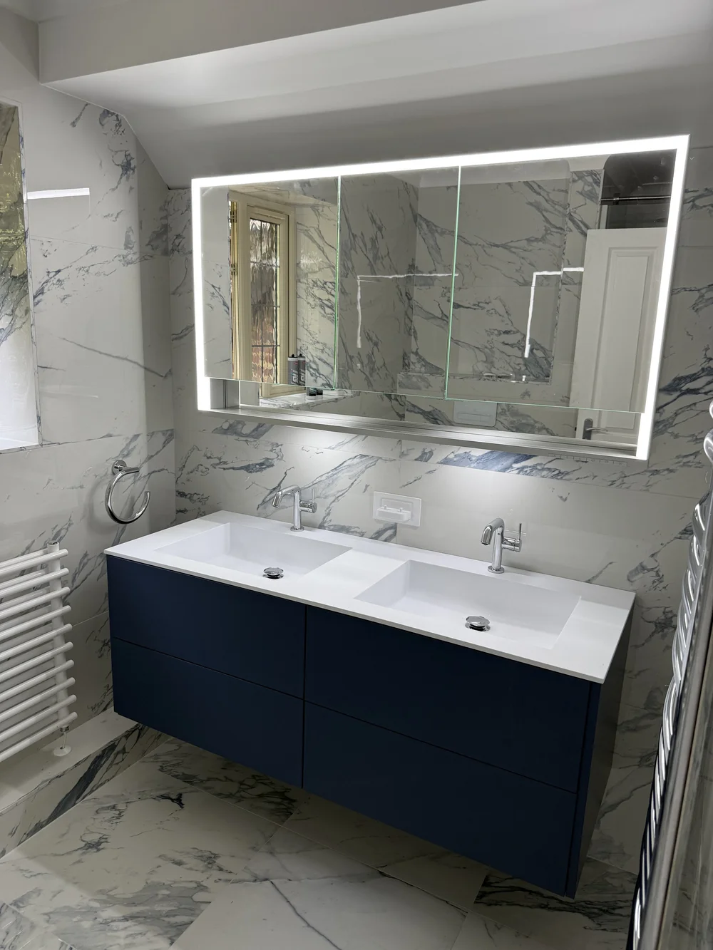 Navy vanity with marble walls and LED mirror — bathroom installation in Sunningdale