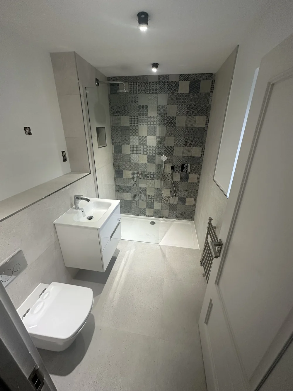 Compact shower room with patchwork feature wall and floating white vanity — bathroom installation in Sunningdale